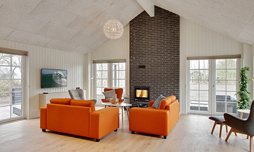 Blick auf einen Wohnbereich mit Sofaecke und Kaminofen in einem dänischen Gruppenferienhaus