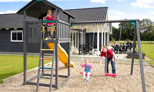 Spielende Kinder auf Spielturm und Schaukel auf dem Grundstück eines Aktivitätshauses